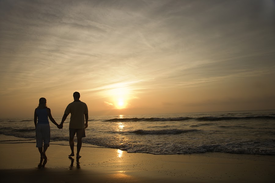 Two people holding hands on the beach.