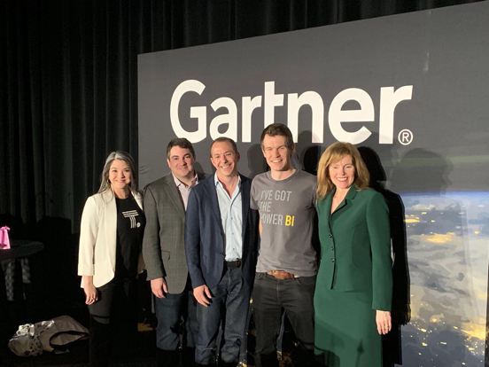 People standing in front of a Gartner sign.