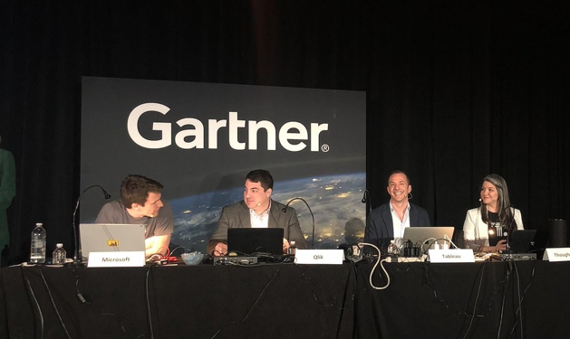 People sitting on a stage with a sign that says gartner behind them.