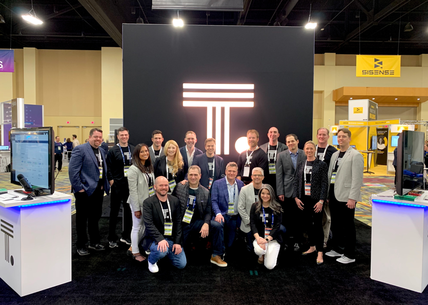 People posing in front of the ThoughtSpot booth.